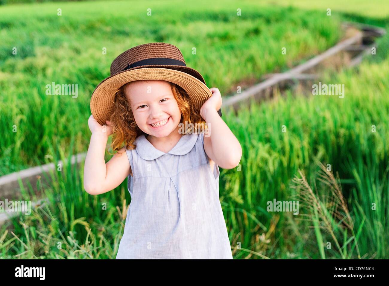 Child girl in straw hat. Cute kid looking at nature lanscape background. Adventure travel concept in retro style Stock Photo