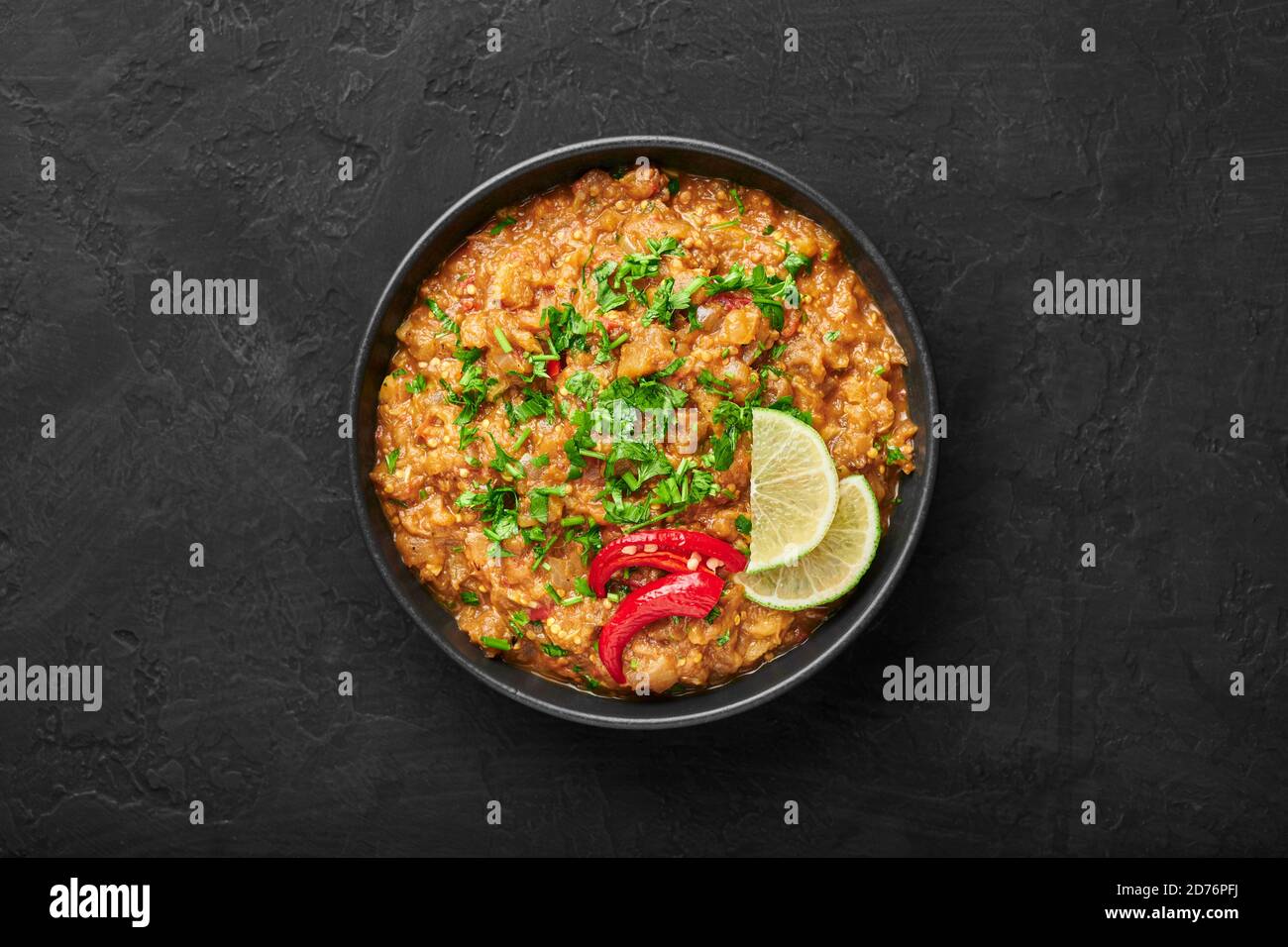 Baingan Bharta or Roasted Mashed Eggplant in black bowl on dark slate table top. Bhurta is indian cuisine puree dish of fire roasted eggplant and masa Stock Photo
