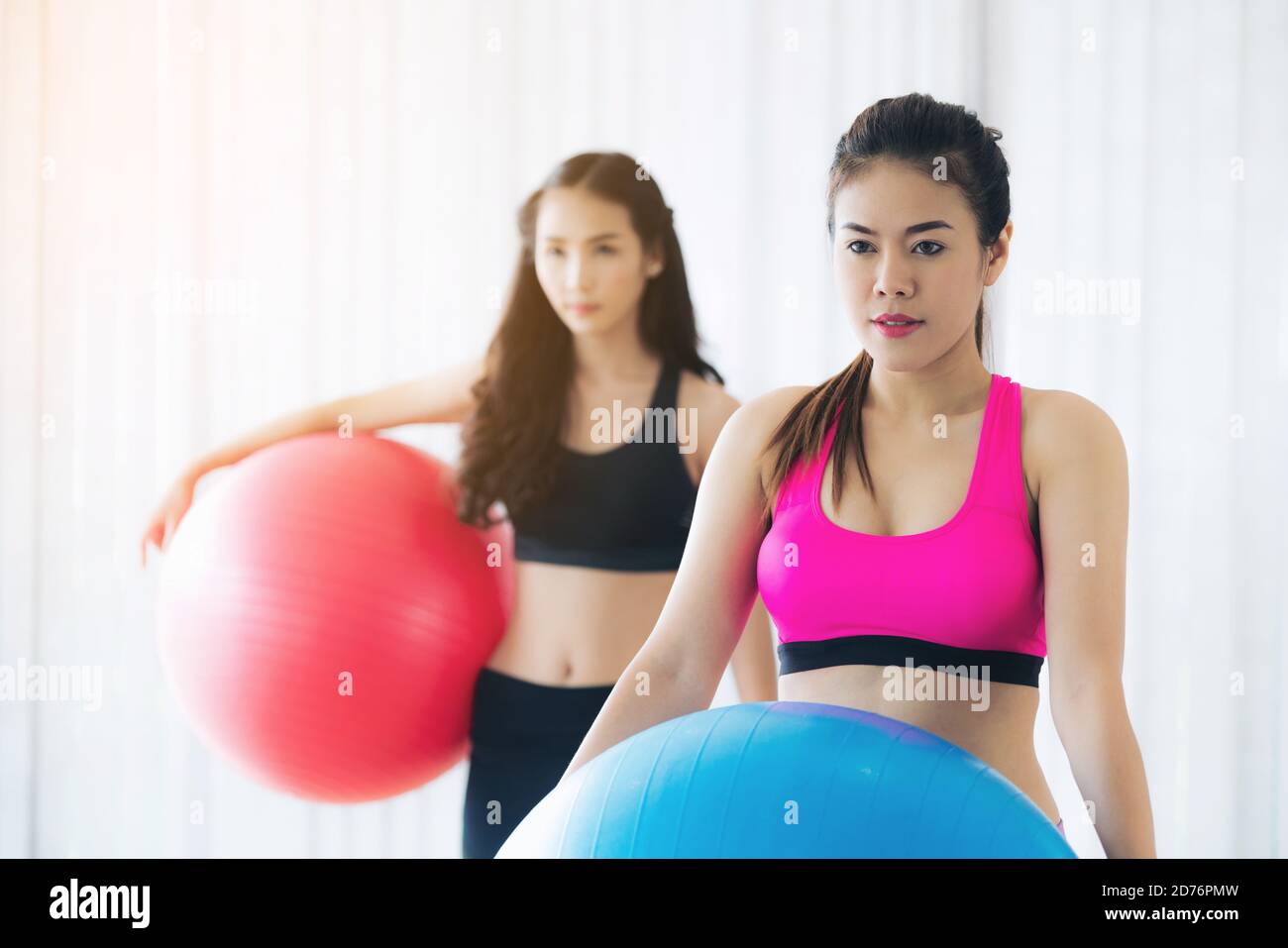 Two healthy woman holding fit ball in fitness gym group class exercise ...