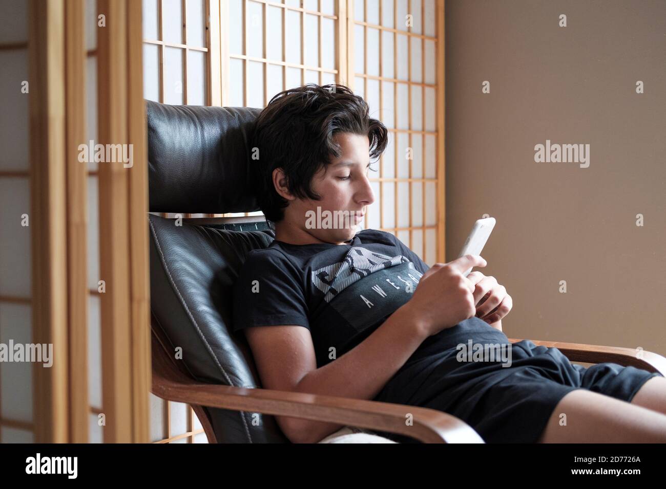 Bored teenage boy, age 13 , on his phone Stock Photo