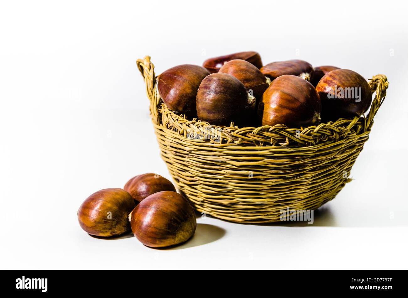 Chestnuts in wicker basket on white background Stock Photo