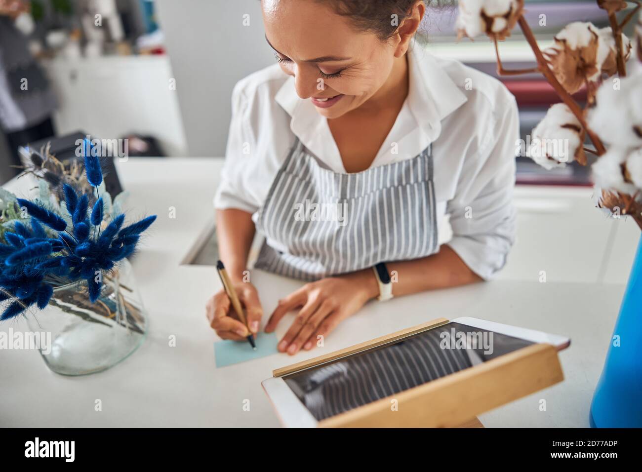 Gladsome lady holding a pen and writing a note Stock Photo