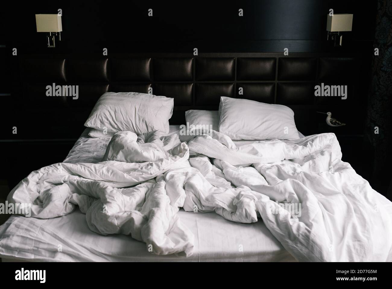 Bed with white linens. Crumpled sheets and pillows after a night's