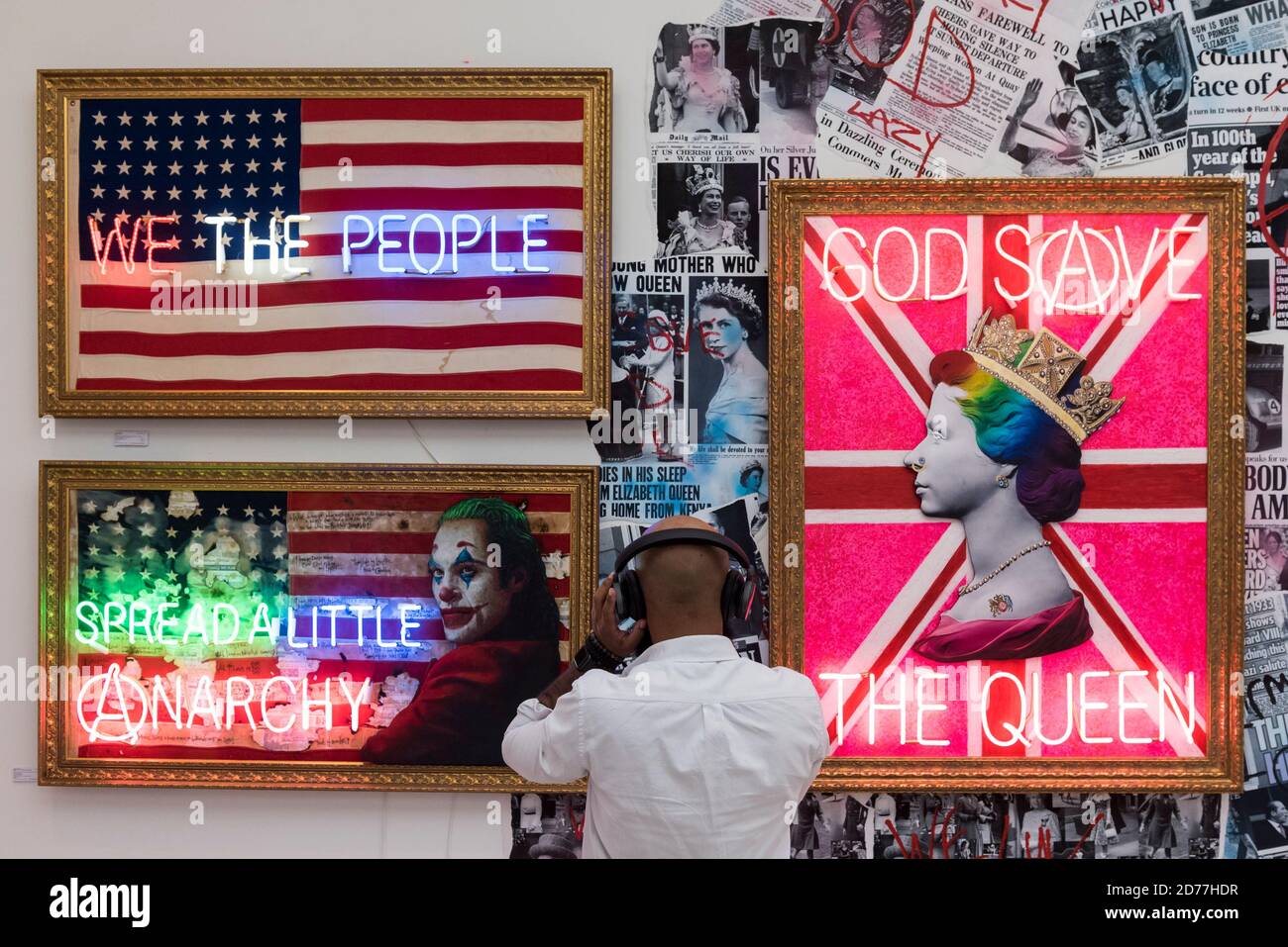 London, UK.  21 October 2020. A visitor views 'Rainbow Punk Queen (Neon)', 2020, 'Spread a Little Anarchy (Joker Neon)', 2020, and 'We The People', 2020, all by Mark Illuminati. Preview of STARTnet Art Fair at the Saatchi Gallery in Chelsea.  The contemporary art fair showcases local London, as well as international, galleries and individual artists from all over the world.  The fair runs 21 to 25 October with Covid-19 protocols in place for visitors.  Credit: Stephen Chung / Alamy Live News Stock Photo