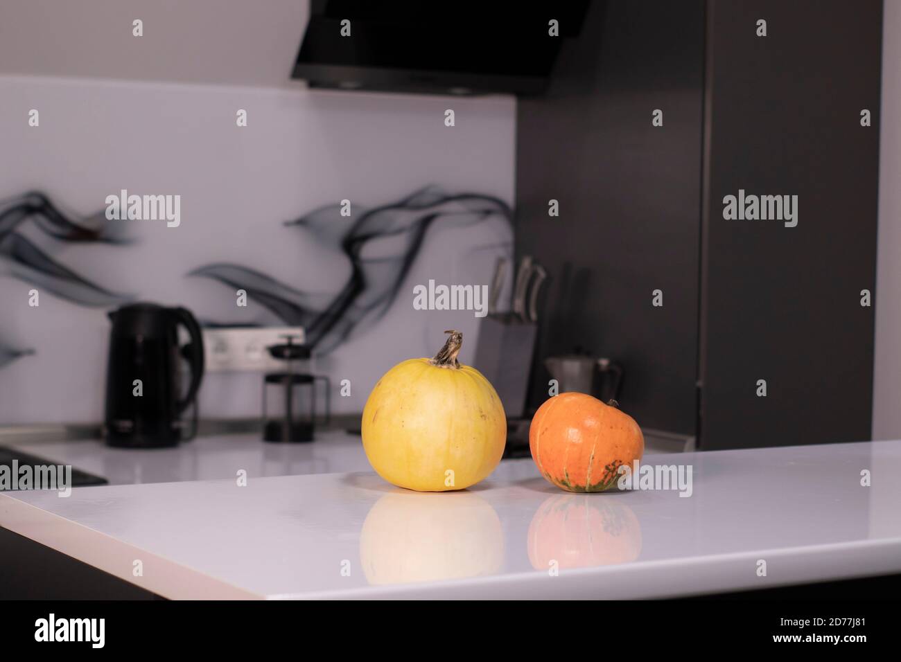 two pumpkins on white table in gray kitchen. halloween concept. Stock Photo