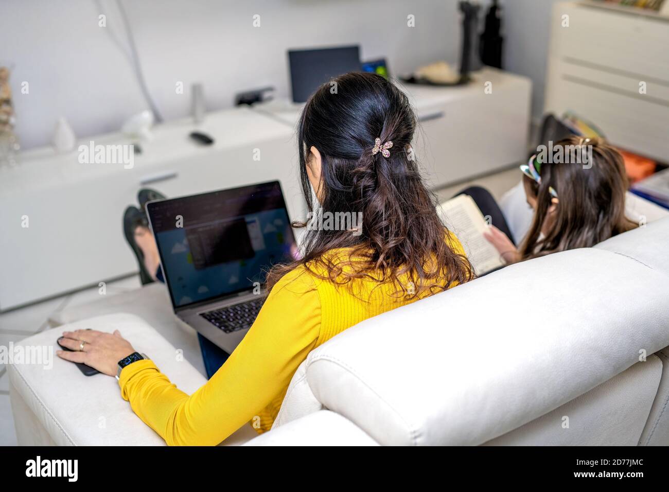 Woman with daugher working at home. Smartworking in covid-19 times. Stock Photo