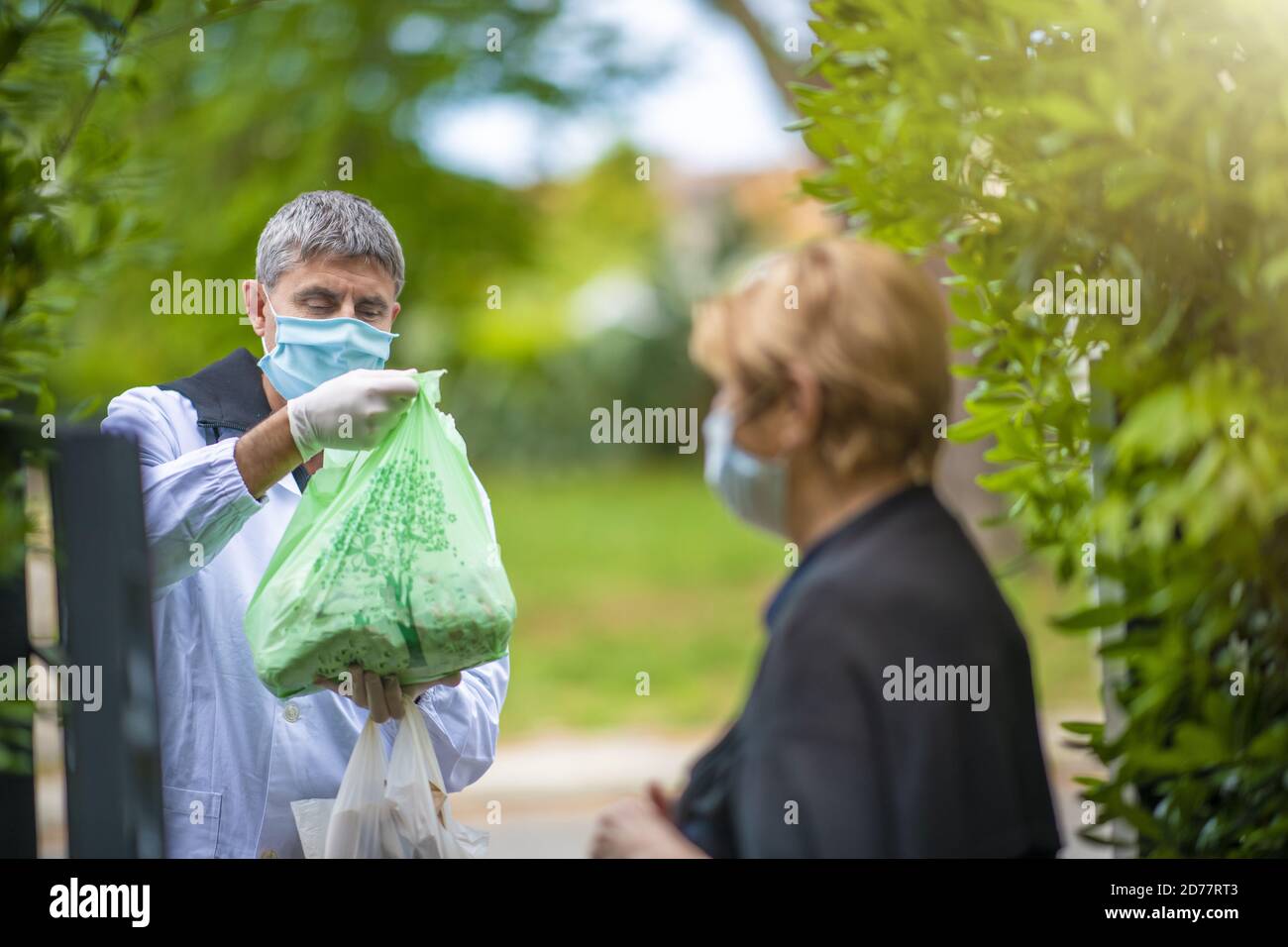 Man bringing groceries at woman's home in covid pandemic . Stock Photo