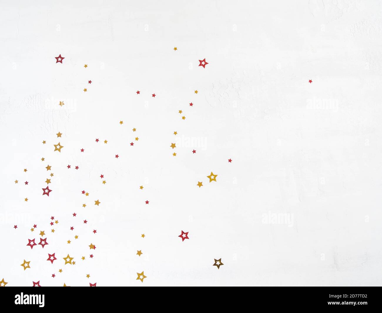 Christmas confetti stars composition. Flat lay of gold and red stars on a white background. Top view. Copy space Stock Photo