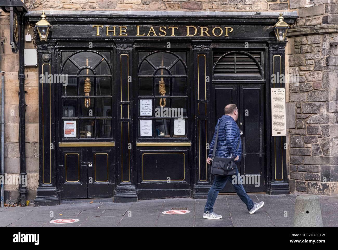 Edinburgh, United Kingdom. 21 October, 2020 Pictured: Scottish First Minister Nicola Sturgeon has ordered pubs in the Central Belt to remain closed until new 5 tier restrictions are introduced on 2 November 2020. A passer-by walks past The Last Drop pub in Edinburgh’s Grassmarket. Credit: Rich Dyson/Alamy Live News Stock Photo