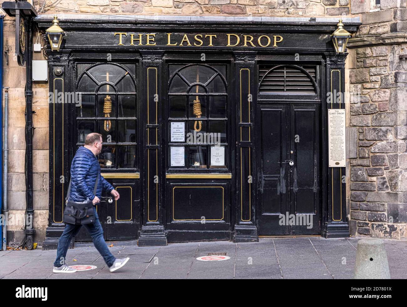 Edinburgh, United Kingdom. 21 October, 2020 Pictured: Scottish First Minister Nicola Sturgeon has ordered pubs in the Central Belt to remain closed until new 5 tier restrictions are introduced on 2 November 2020. A passer-by walks past The Last Drop pub in Edinburgh’s Grassmarket. Credit: Rich Dyson/Alamy Live News Stock Photo