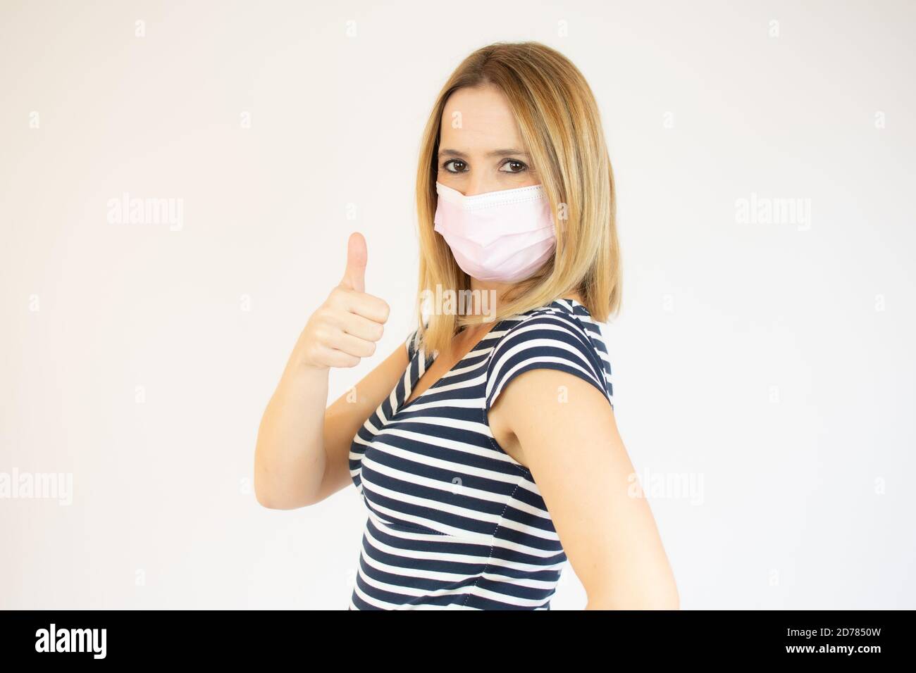 Young woman wearing surgical mask showing thumb up isolated on the ...