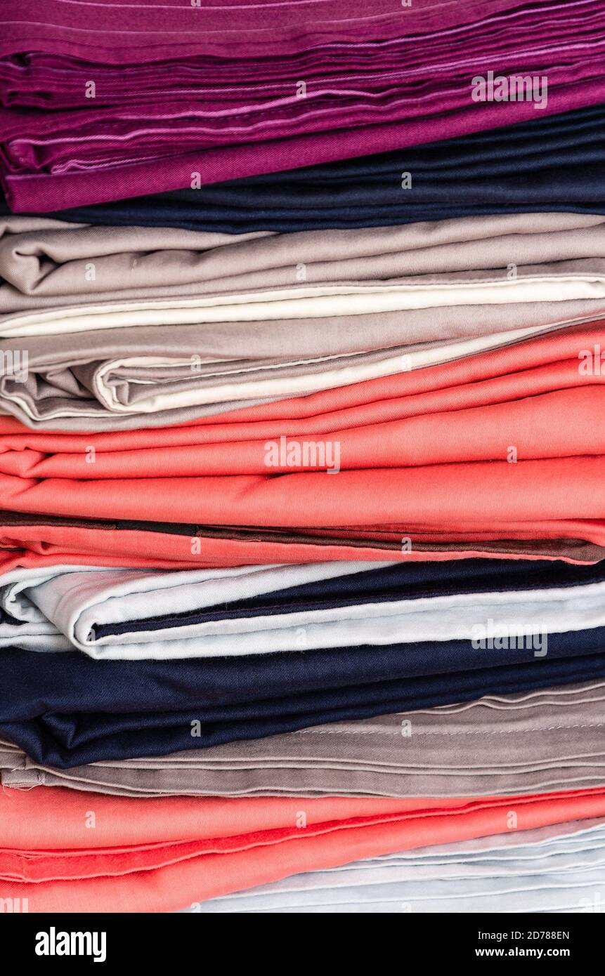 Stack of folded clean colored linens: duvet covers, sheets, pillowcases. The concept of housework and storage. Closeup Stock Photo