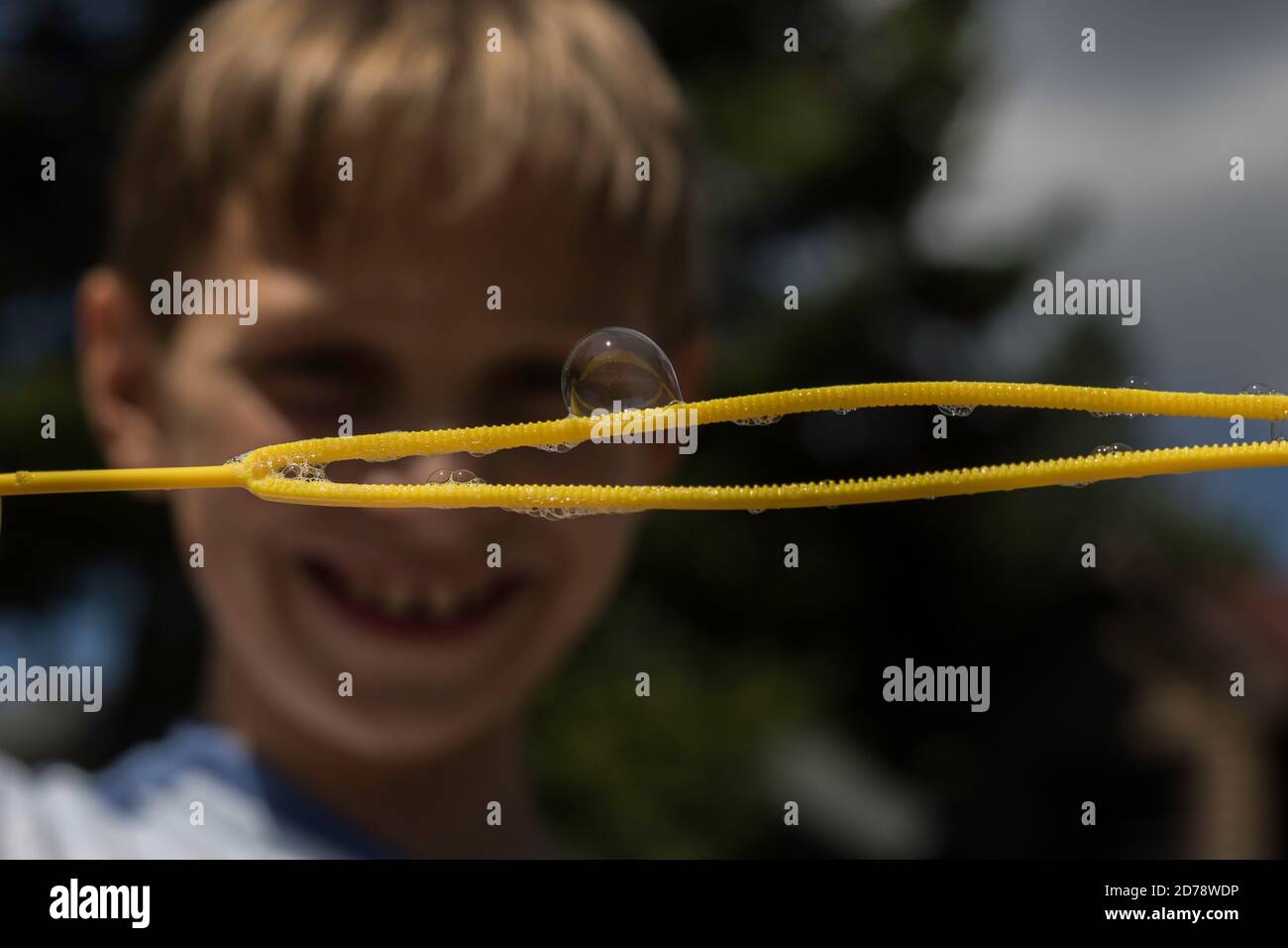 Soap bubble on a wand with boy in a blurred background Stock Photo