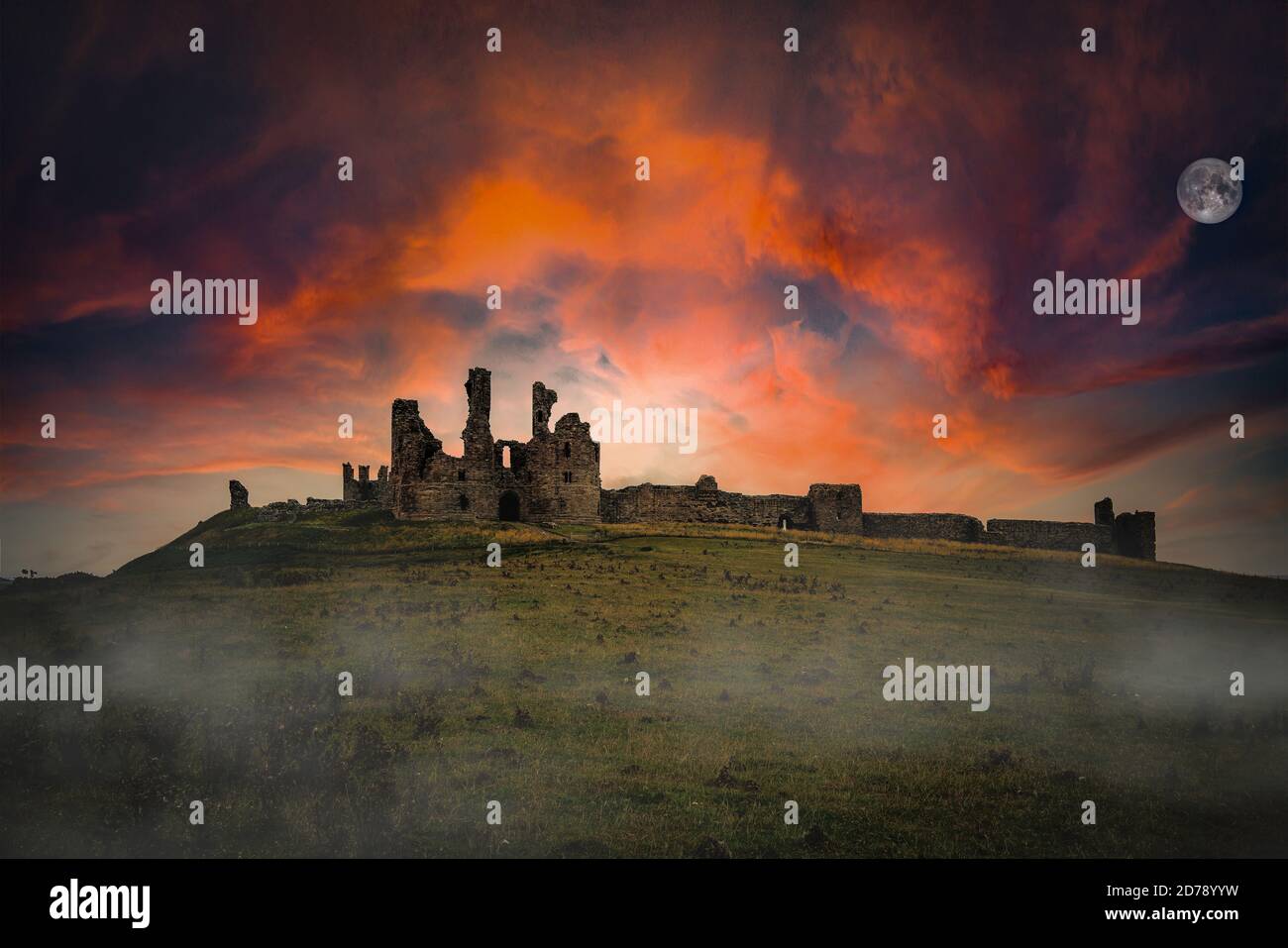 Dawn over Dunstanburgh Castle on the Northumbrian coast. Stock Photo