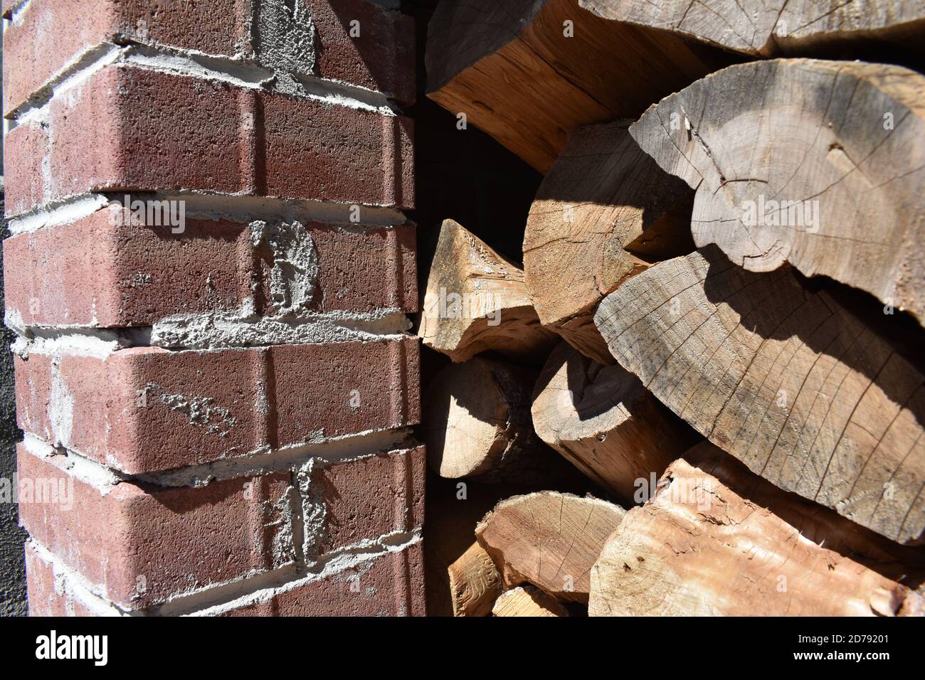 Closeup shot of stacked cedar wood with red brick in a fireplace Stock Photo
