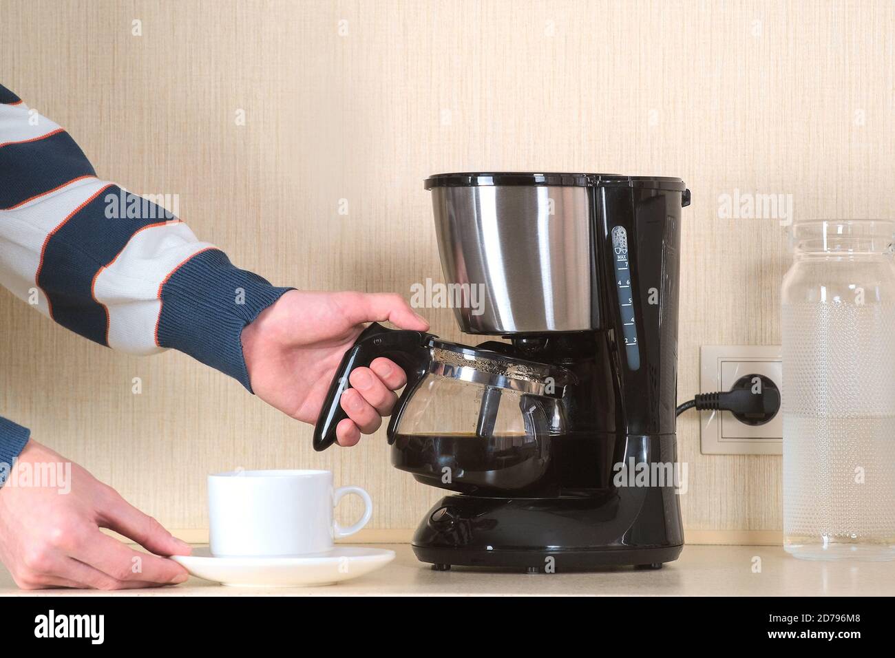 Coffee area in the office. The Manager pours a Cup of coffee from a glass coffee flask during a timeout Stock Photo