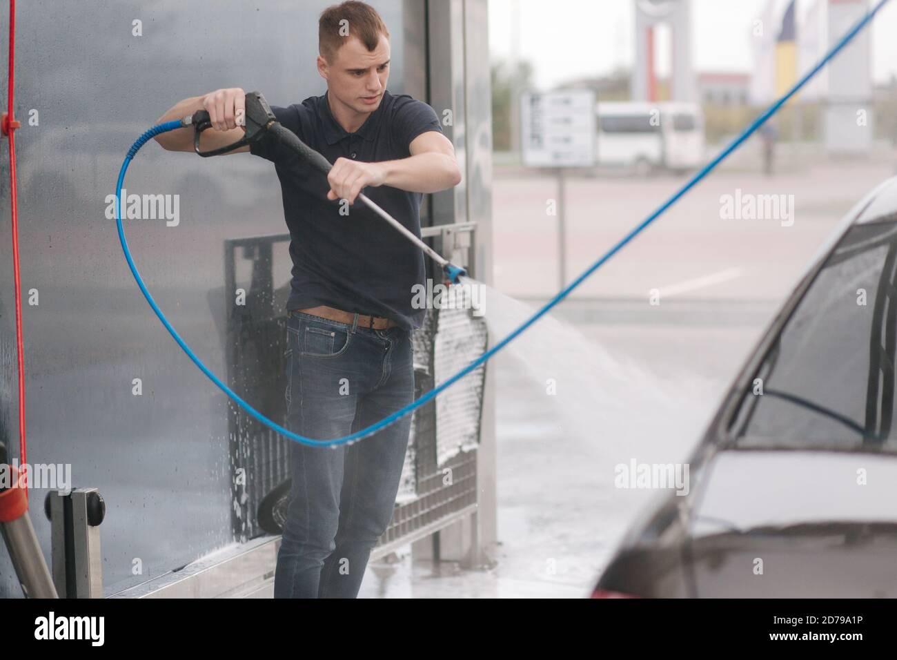 Worker cleaning car using high pressure water Stock Photo