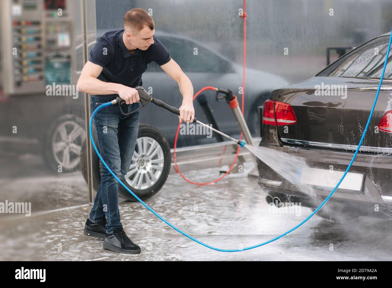 Worker cleaning car using high pressure water Stock Photo