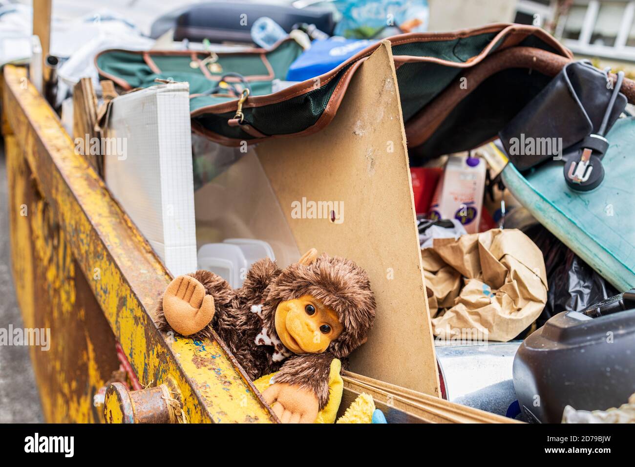 Skip filled with household junk and a cuddly toy monkey, in Kinsale, County Cork, Ireland Stock Photo