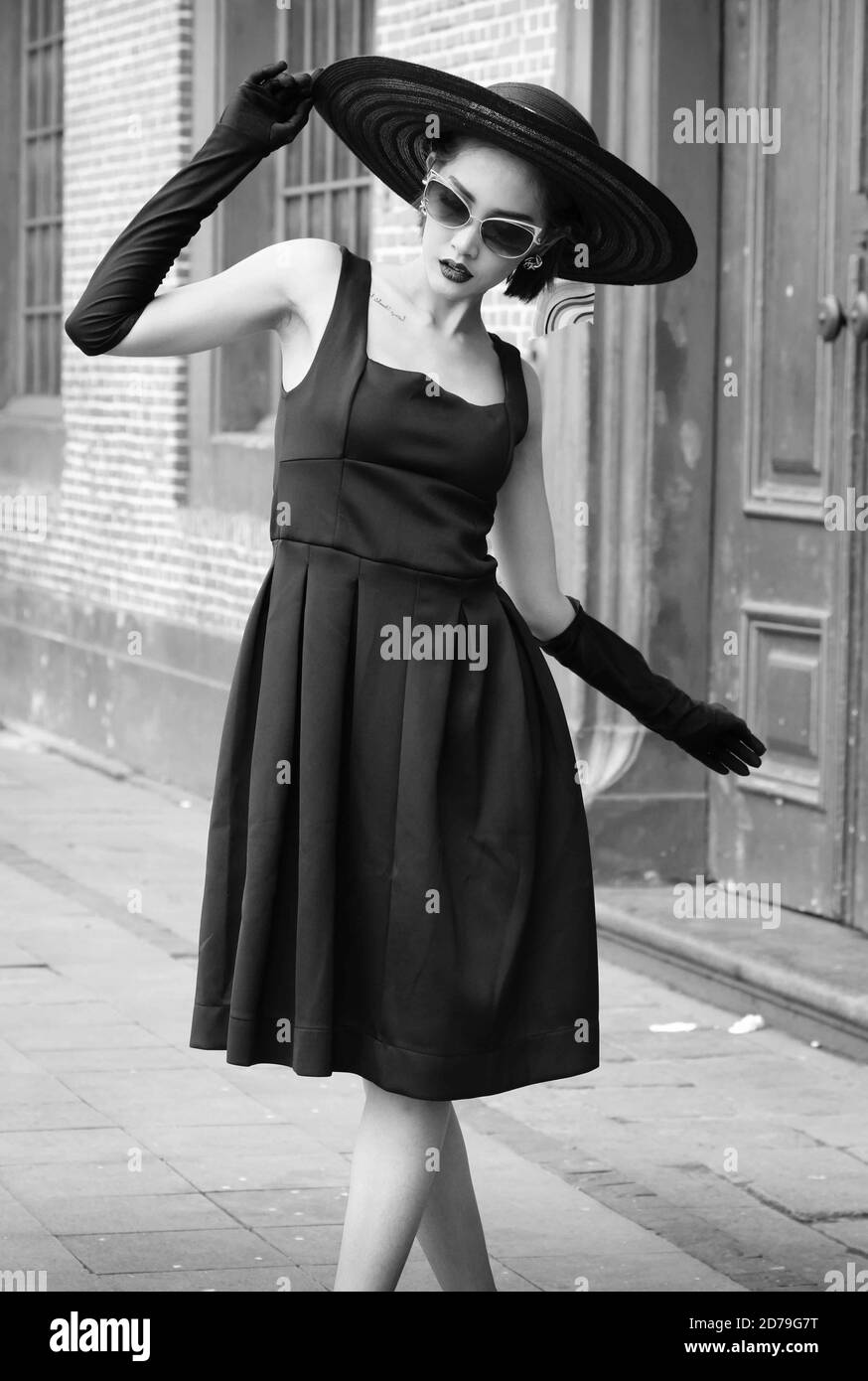 Black and white image of an Indonesian woman in a stylish pose looking down. Stock Photo