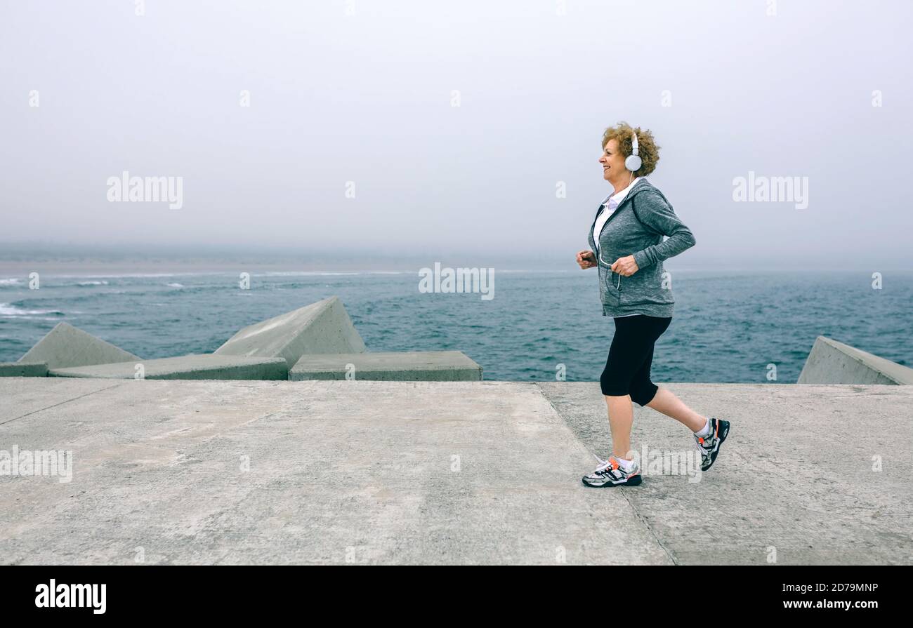 Senior sportswoman with headphones running Stock Photo