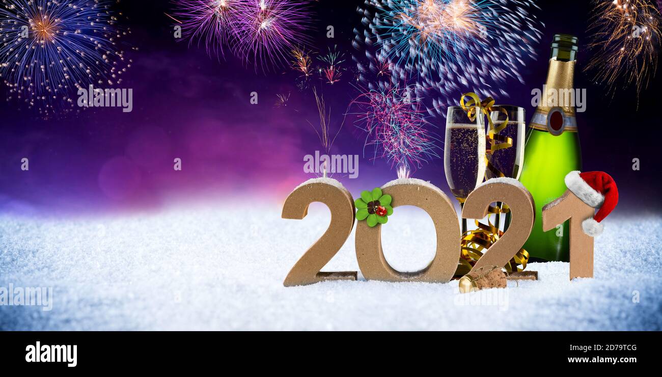 happy new year eve 2021 number colorful fireworks with santa hat four leaf clover champagne bottle glass on snow front of red purple blue black bokeh Stock Photo
