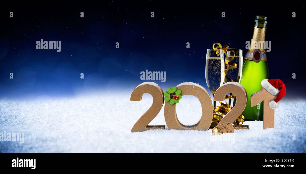 happy new year 2021 number with santa hat four leaf clover champagne bottle glass on snow front of blue black bokeh night panorama  background Stock Photo