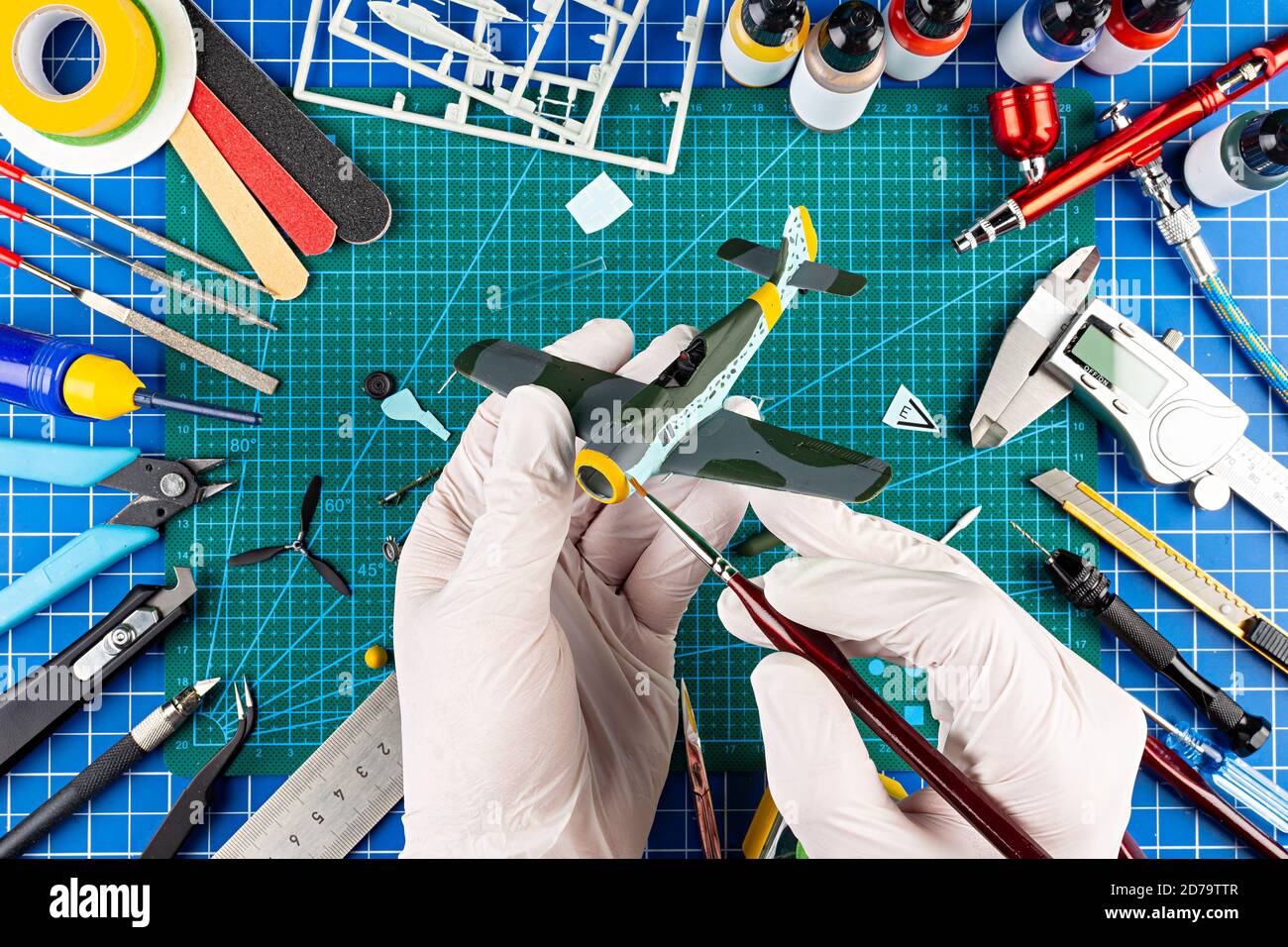 desktop view from above of assembly and painting of retro scale model fighter plane concept background. modeling tools airbrush gun paint kit parts bl Stock Photo