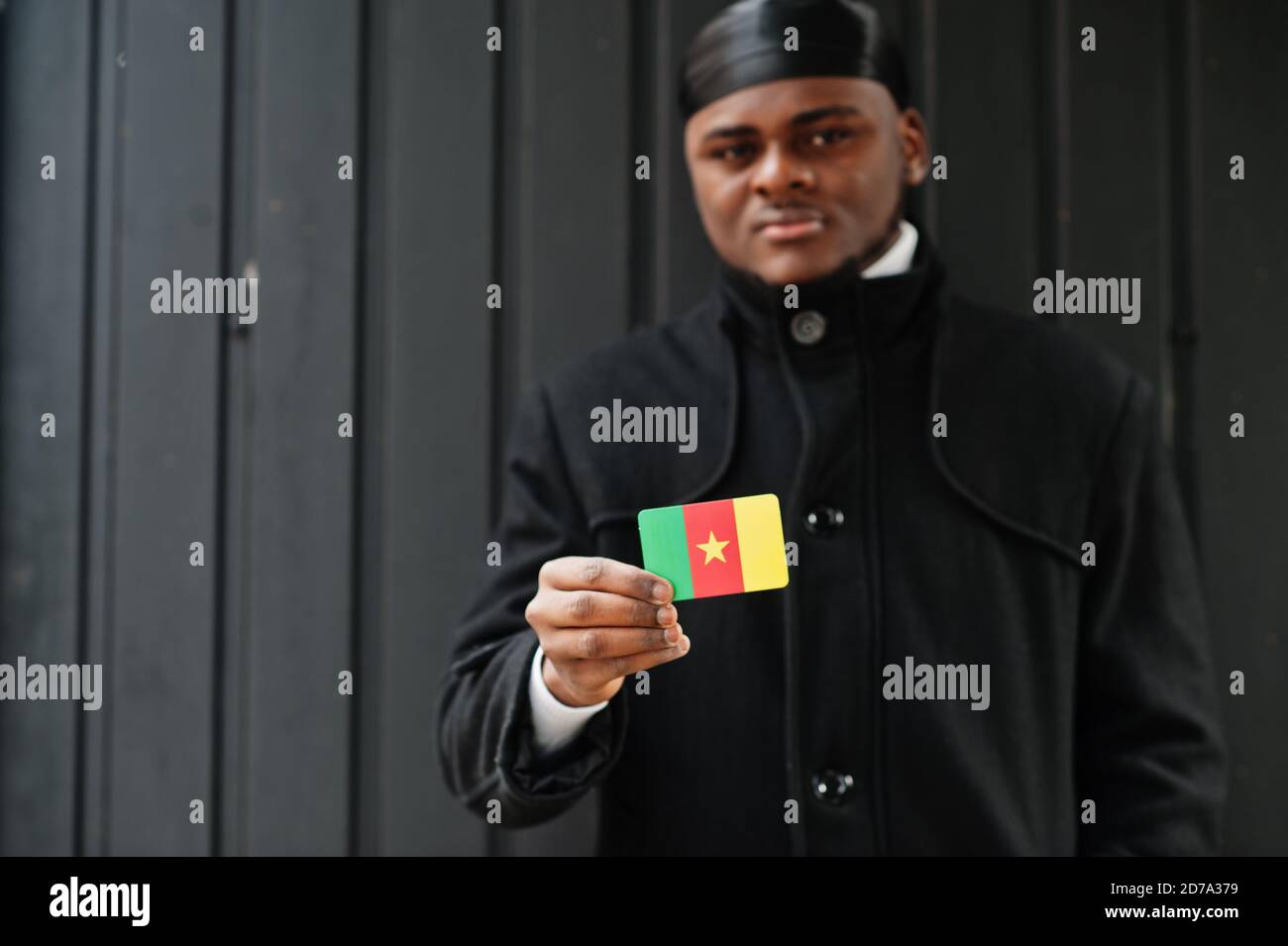 African man wear black durag hold Ghana flag at hand isolated dark background. Stock Photo