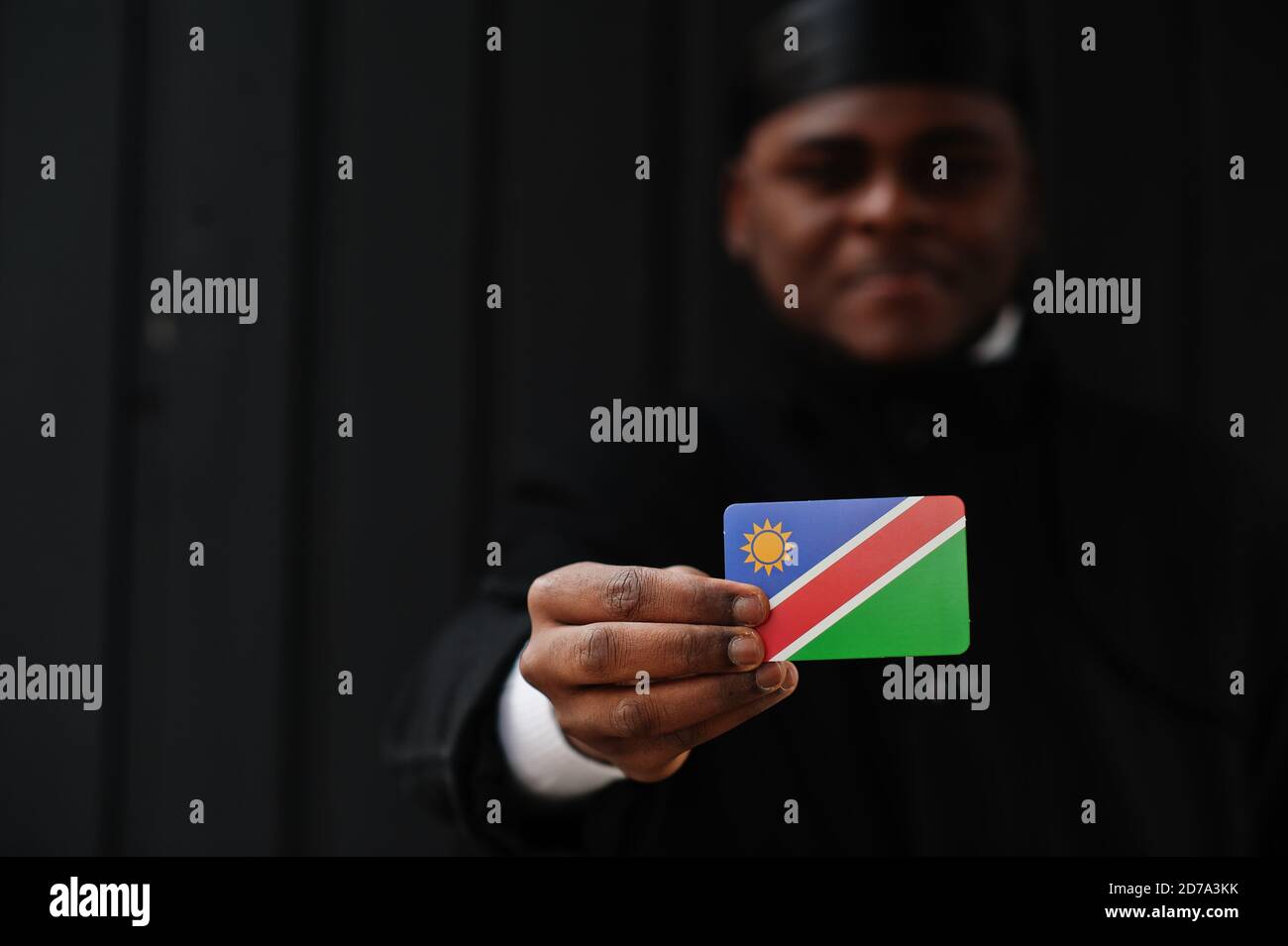 African man wear black durag hold Namibia flag at hand isolated dark background. Stock Photo