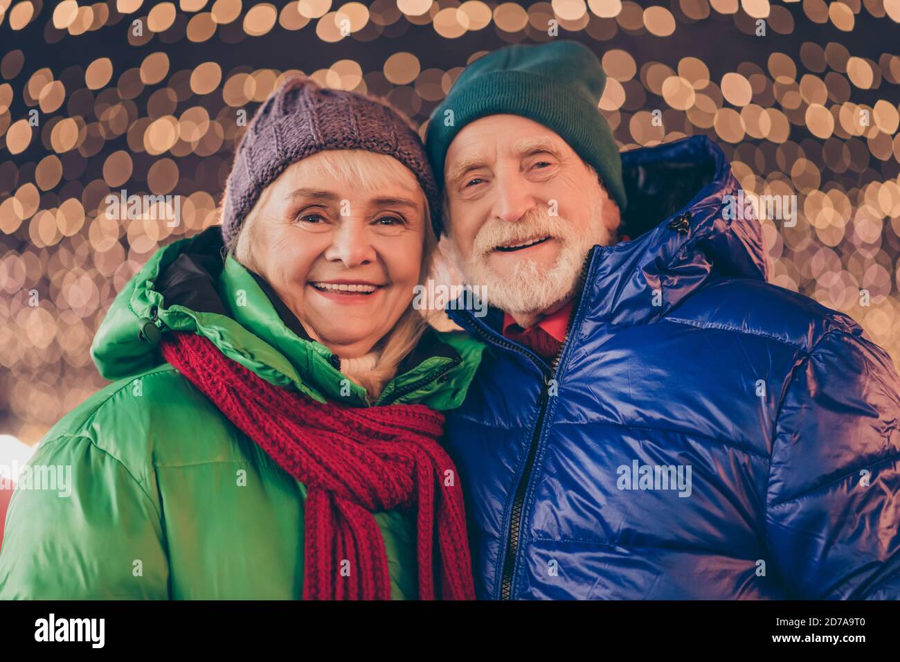 Photo of adorable old married couple woman man enjoy x-mas christmas jolly holly celebration outdoors in evening lights wear outerwear headwear hat Stock Photo