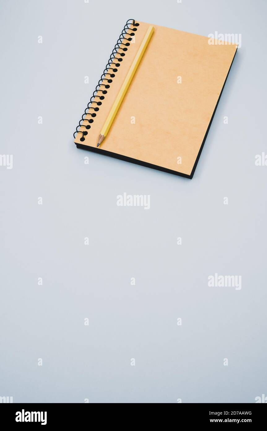 Vertical shot of a notebook and pencil on a blue surface Stock Photo