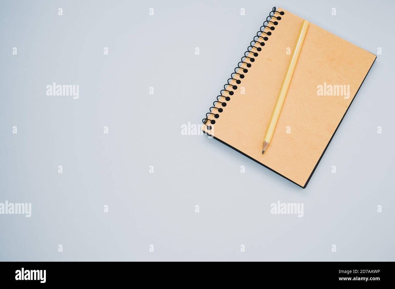High angle shot of a notebook and a pencil on a blue surface Stock Photo