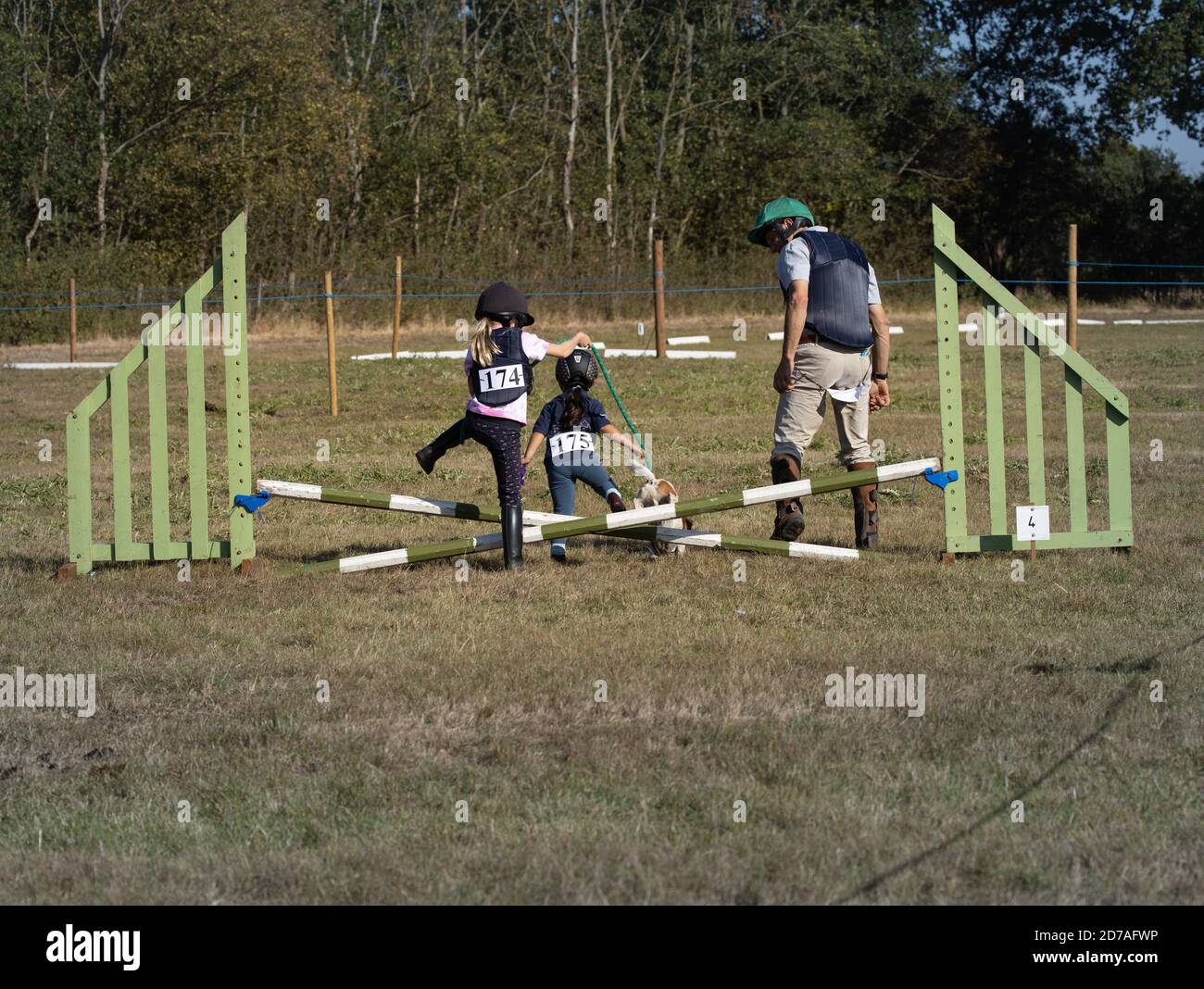 Kids and dad playing together having fun with pet dog jumping horse show jump without a horse Stock Photo