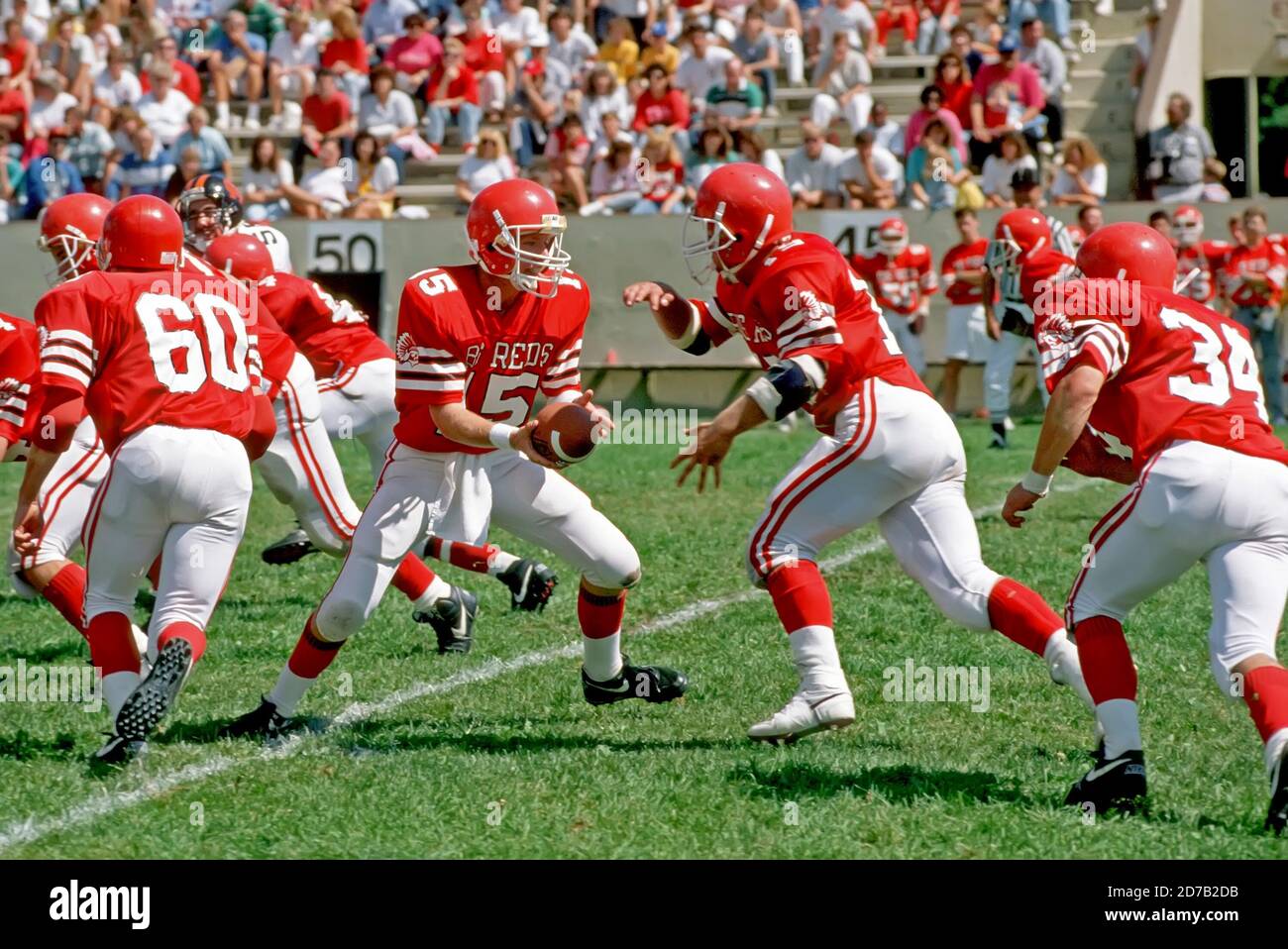 High School football action - quarterback hands off ball to running back Stock Photo