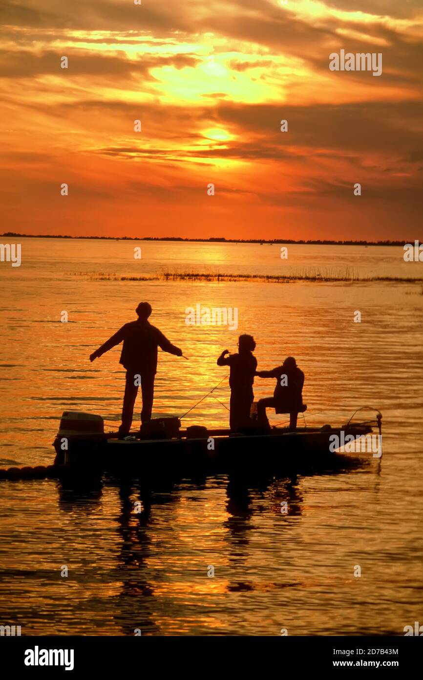 Family bass fishes on Lake Okeechobee, Florida against a sunset Stock Photo
