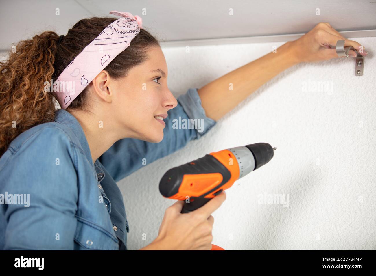 young handywoman drilling on the ceiling Stock Photo