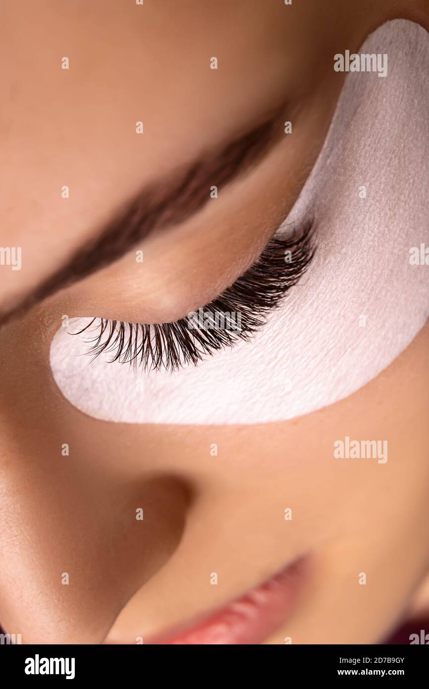 Eyelash Extension Procedure. Close up view of beautiful female eye with long eyelashes, smooth healthy skin. Stock Photo