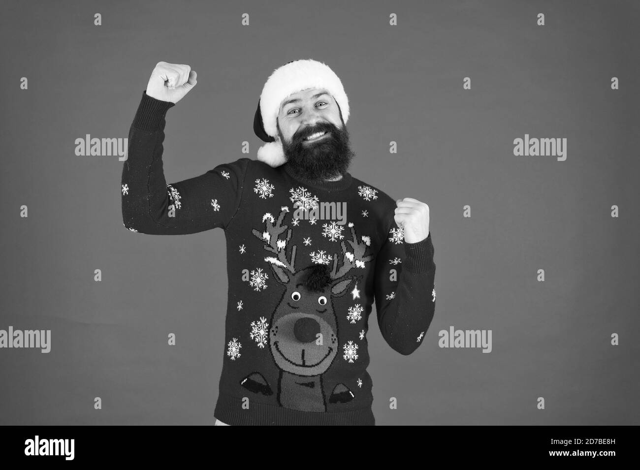 Start this party. Happy new year celebration. Join holiday celebration. Winter party outfit. Sweater with deer. Hipster bearded man wear winter clothes red background. Christmas celebration ideas. Stock Photo