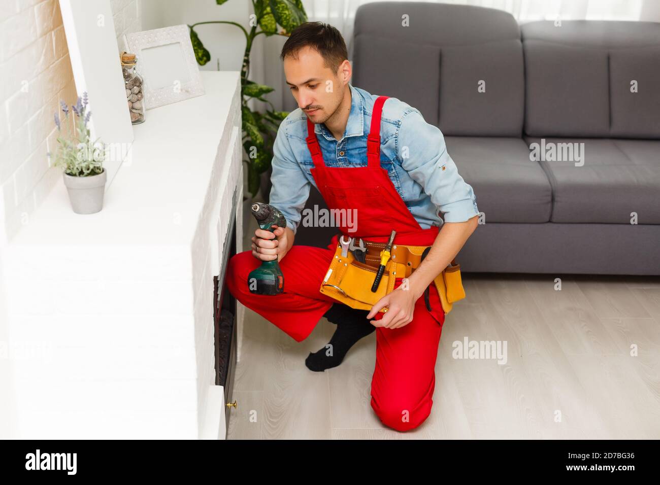 repairman repairs and installs a fireplace in the apartment Stock Photo