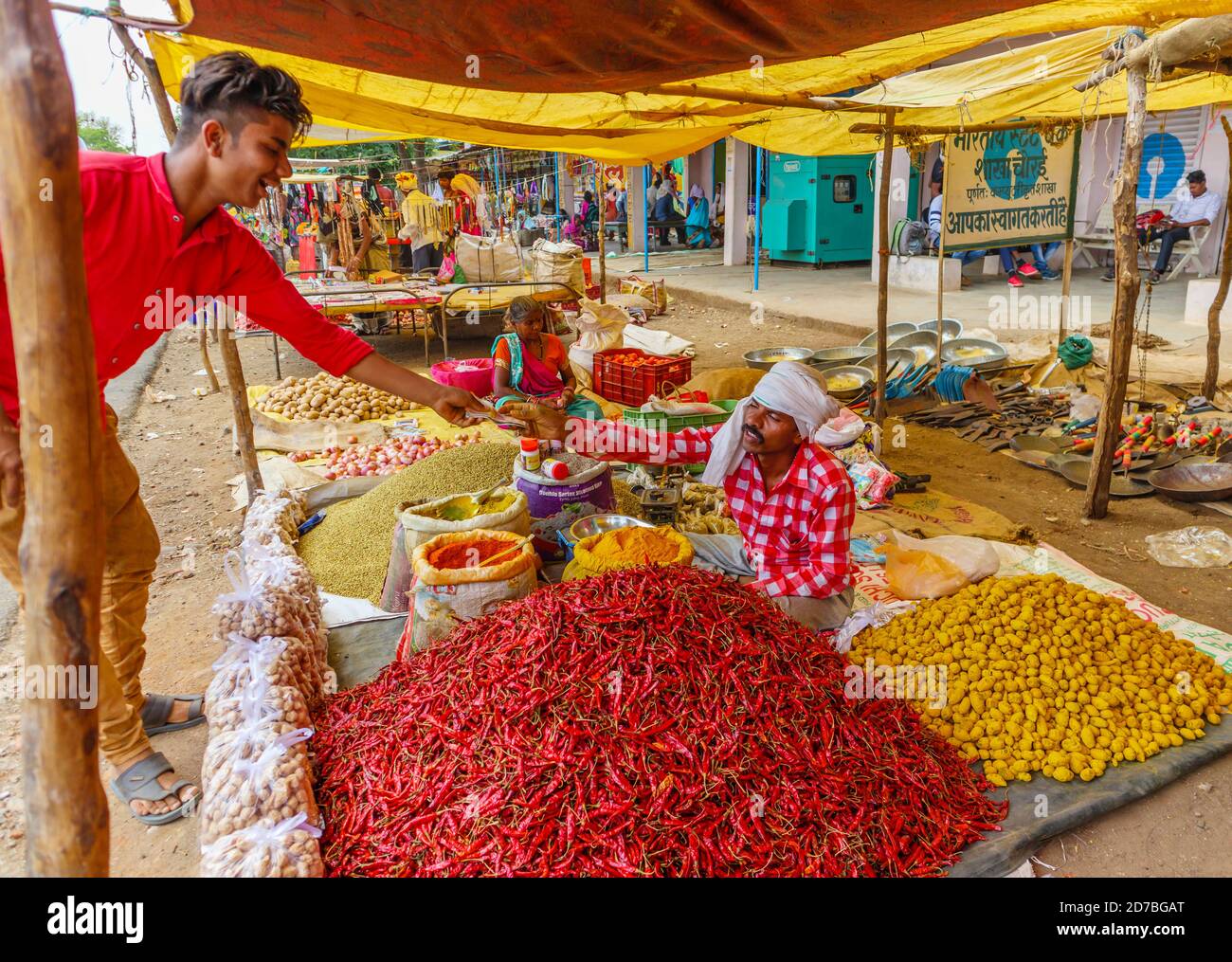 Customer buying and paying for food at a stall selling chillies, spices and local produce in a roadside market in a village in Madhya Pradesh, India Stock Photo