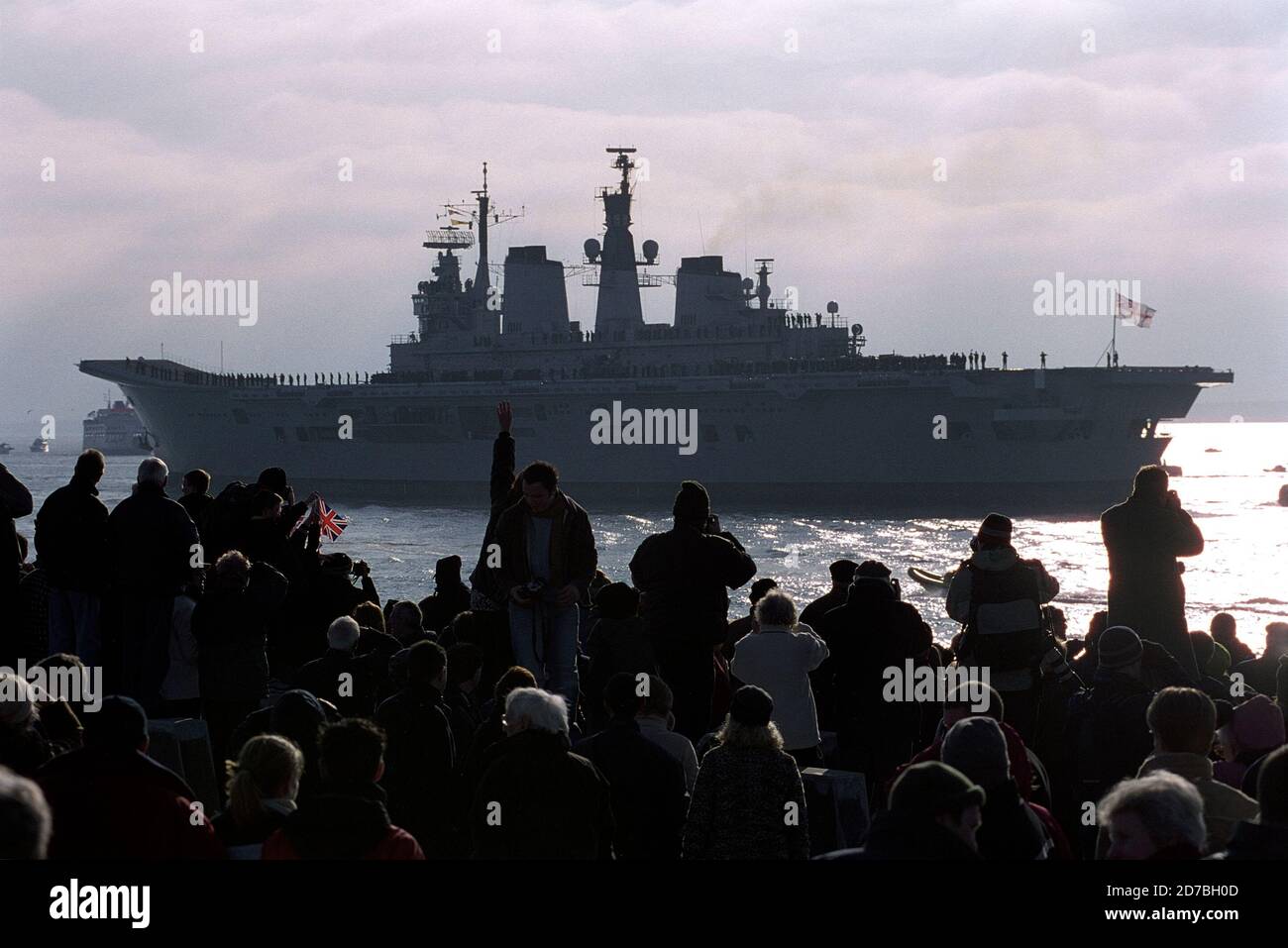 AJAXNETPHOTO. 11 JAN 2003. PORTSMOUTH, ENGLAND. - ARK LEAVES - (PMO5) -  HMS ARK ROYAL LEAVES PORTSMOUTH BOUND FOR 'SOMEWHERE' EAST OF SUEZ. THOUSANDS OF WELL WISHERS GATHERED ON THE CITY'S OLD HOT WALLS RAMPARTS TO SEE THE CARRIER OFF.  PHOTO:JONATHAN EASTLAND/AJAX.  REF:3 13 01 5 Stock Photo