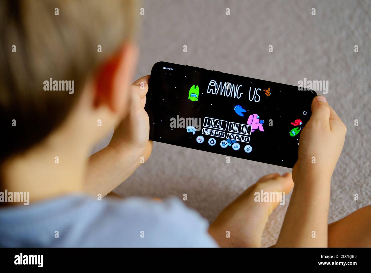 Manchester / United Kingdom - October 21, 2020: Among Us game seen on the smartphone screen and child playing it. New popular app. Stock Photo