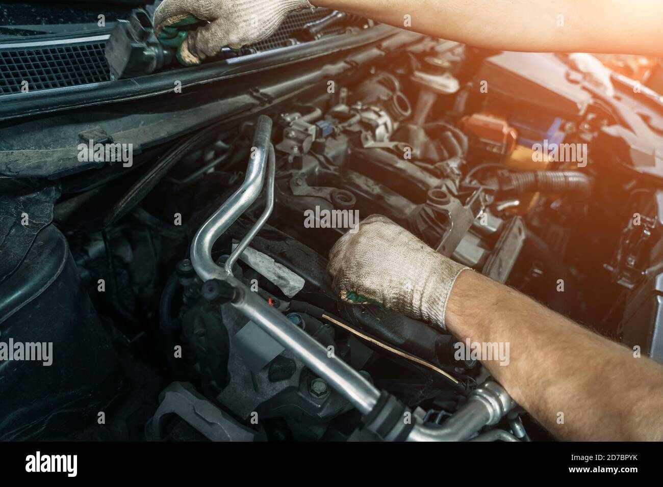 Worker repairing car and changes spark plugs in car engine in auto service, close up. Stock Photo
