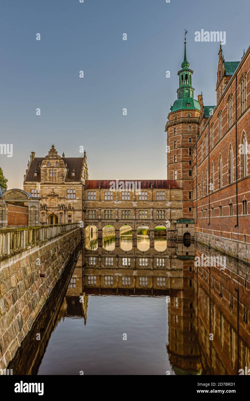 Frederiksborg castle and bridge over the moat are reflected in the shiny water an early morning at sunrise, Hillerod, Denmark, October 17, 2020 Stock Photo