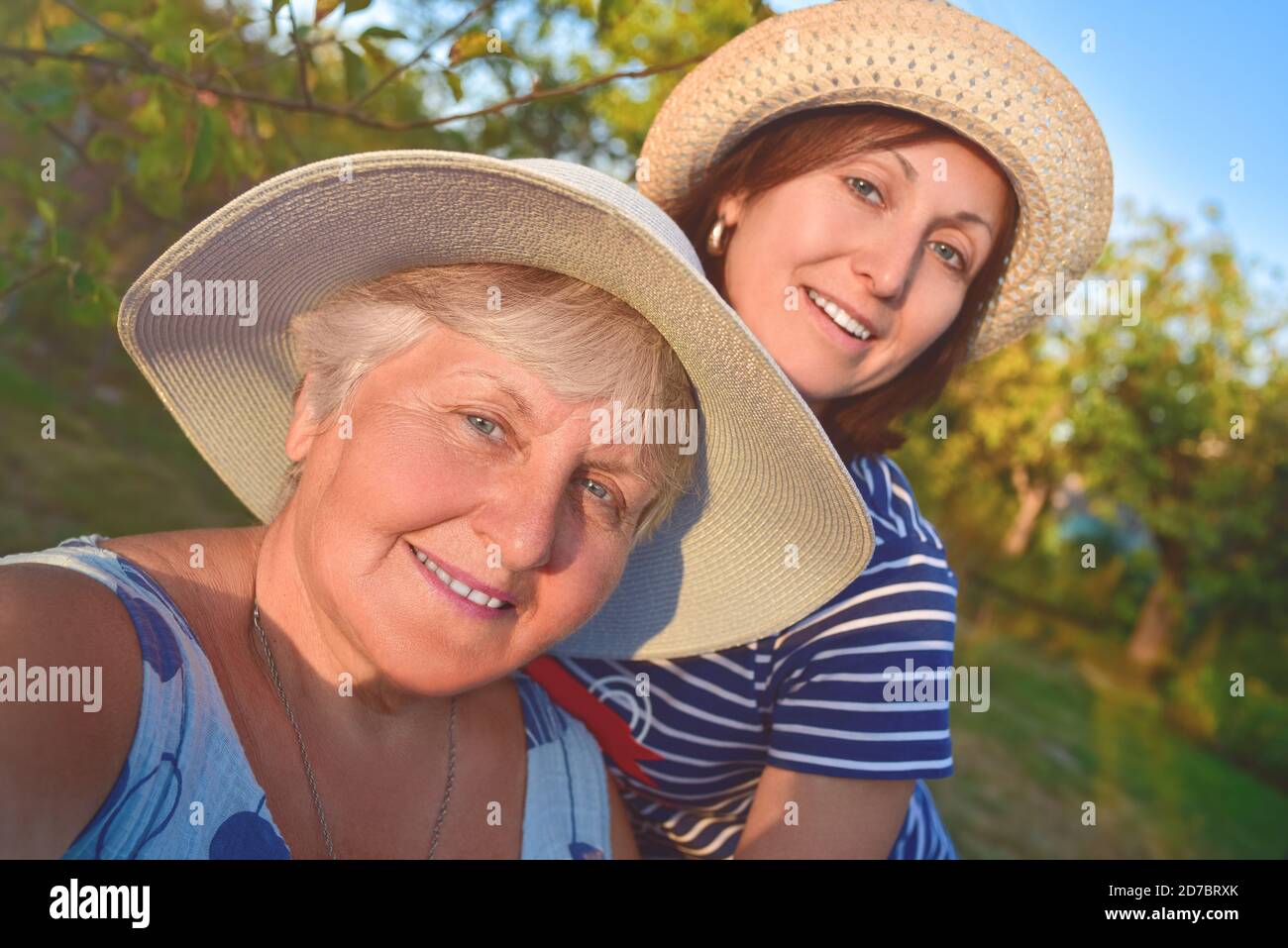 portrait of a happy elderly woman hugging her daughter and makes selfie at the park Stock Photo