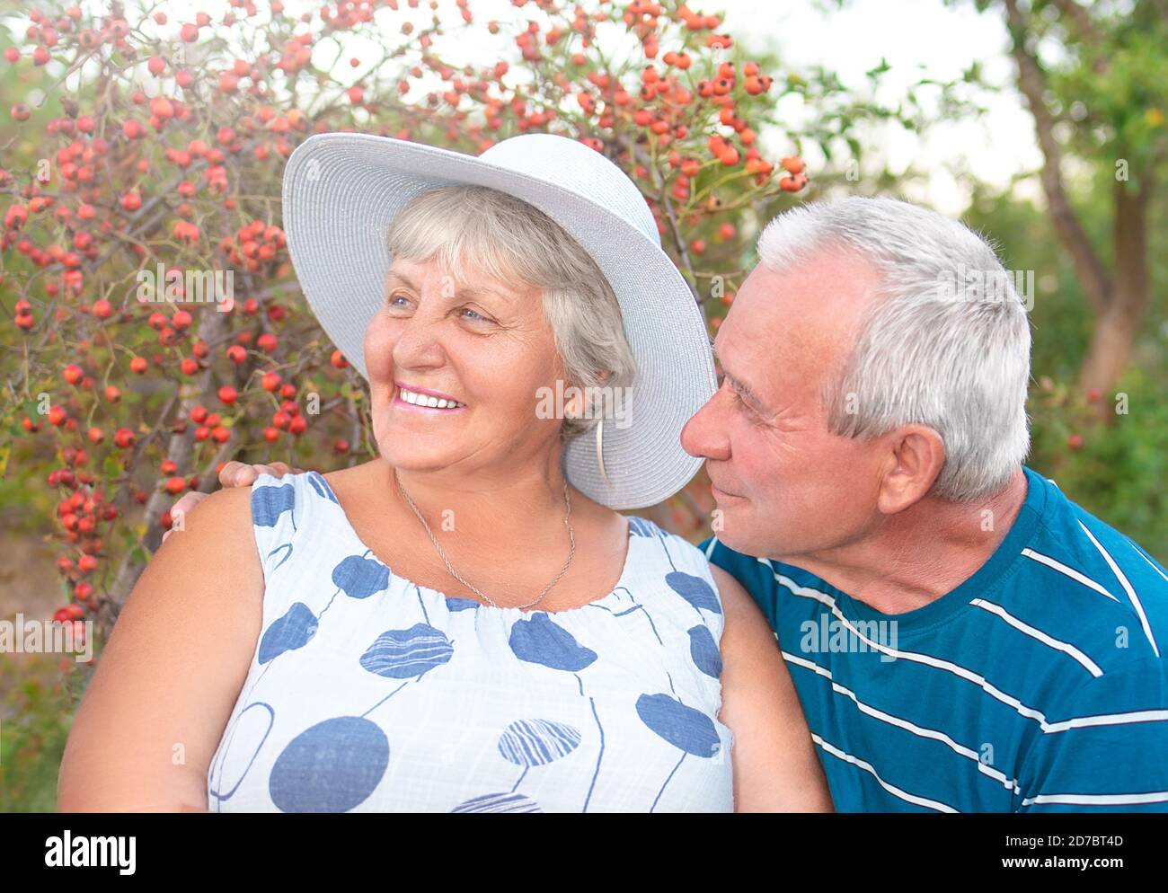 Authentic outdoor shot of aging couple having fun in the garden and blessed with love. During their game man is trying to kiss his partner and she is Stock Photo