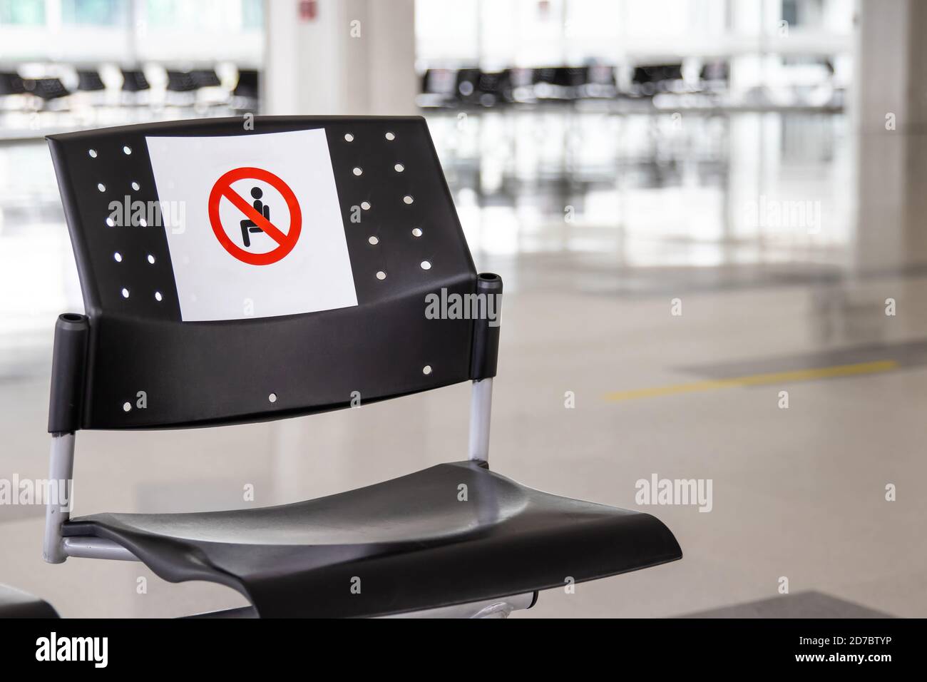 Empty waiting room at an airport during COVID-19 pandemic with social distancing signs on chairs Stock Photo