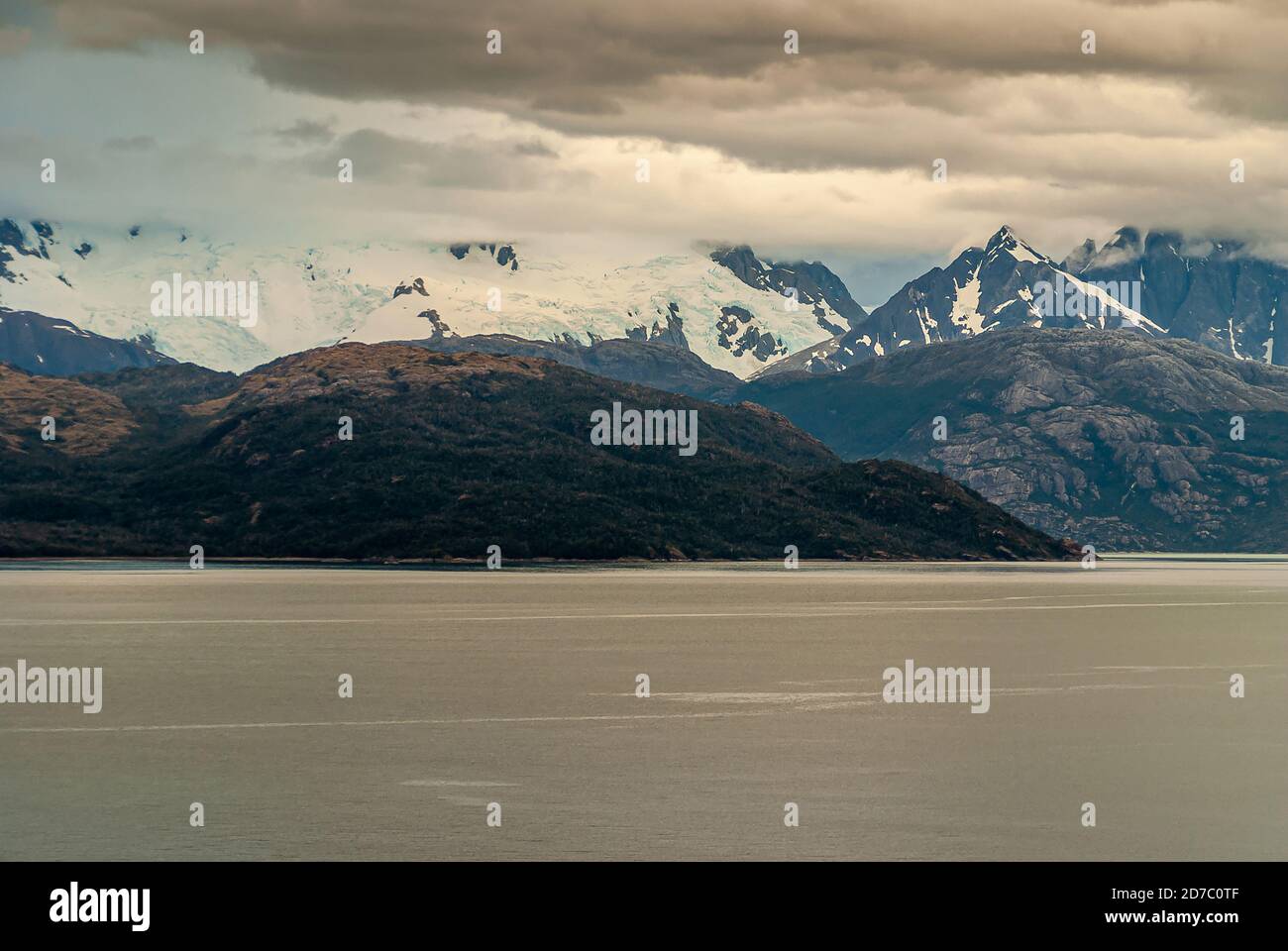 Sarmiento Channel, Chile - December 11, 2008: Amalia Glacier and Fjord. White cloudscape hides part of glacier ice field on rocky mountain. More brown Stock Photo