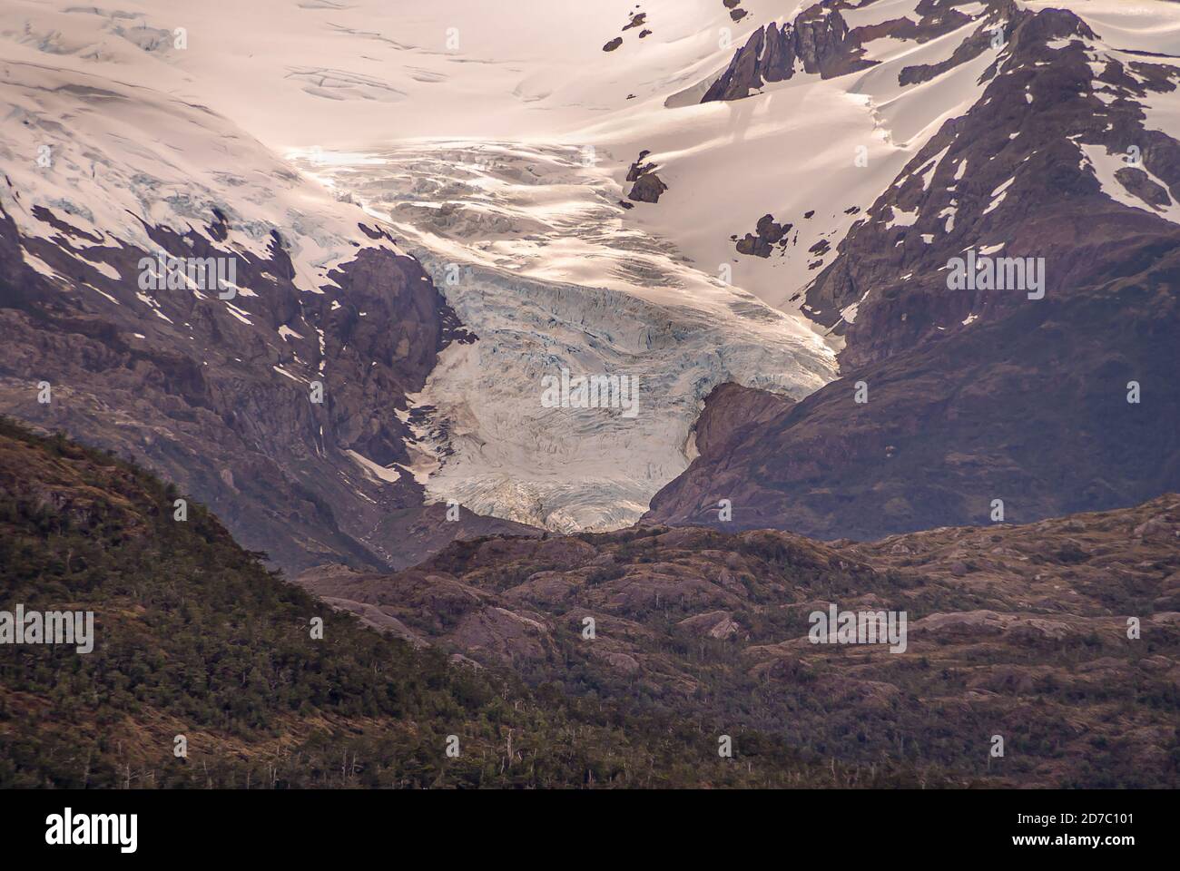 Sarmiento Channel, Chile - December 11, 2008: Closeup of Amalia Glacier above belt of brown rocks and green foliage. Stock Photo